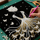 Handcrafting a decorative design with pearls and gold thread on black paper.