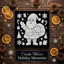 A square black holiday art print featuring a white dotted Santa Claus design surrounded by snowflakes, candy canes, gifts, and trees, displayed on a dark wood surface with pinecones, dried orange slices, fairy lights, and a sign reading 'Create Warm Holiday Memories'.