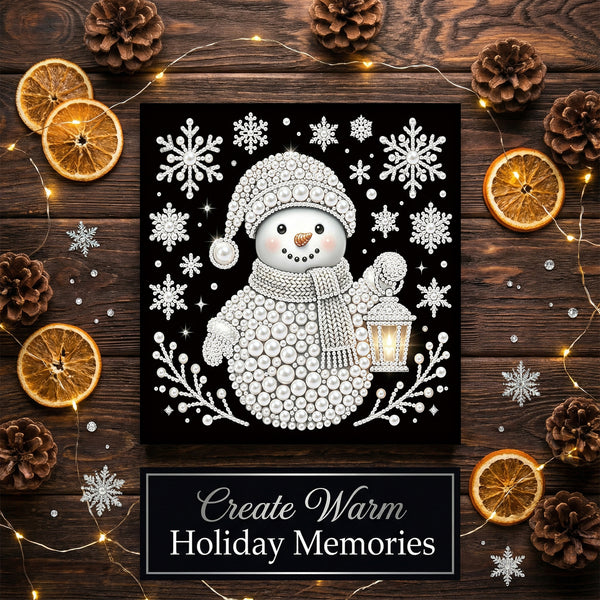 A square black-and-white holiday art print featuring a knitted snowman holding a lantern, surrounded by snowflakes and branches. The print is displayed on a dark wood surface with pinecones, dried orange slices, fairy lights, and a banner reading 'Create Warm Holiday Memories'.
