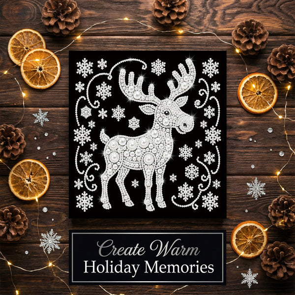 A square black holiday art print featuring a white reindeer and snowflakes, styled on a dark wood surface with pinecones, dried orange slices, fairy lights, and a banner reading 'Create Warm Holiday Memories'.