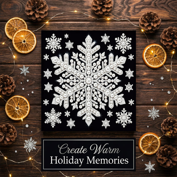 A square black canvas or print featuring a large white ornate snowflake with smaller snowflakes around it, styled on a dark wood surface with dried orange slices, pinecones, fairy lights, and silver snowflake decorations. A label at the bottom reads 'Create Warm Holiday Memories'.