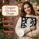 A woman in a cream knit sweater holds a black square ornament panel decorated with white pearl-like embellishments and a Christmas gingerbread design. The scene is festive with warm holiday lights, pine branches, and text overlays describing the compact 25x25cm design, space adapter versatility, emotional meaning, Christmas theme, and pearl details.