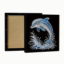 A square black canvas or framed print shown from the back and front. The front features a rhinestone-style dolphin design in shades of blue, silver, and white over a black background.