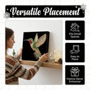 A woman in a patterned sweater is holding a black canvas wall art piece featuring a colorful jeweled hummingbird. The image includes marketing text reading 'Versatile Placement' and three black feature tiles stating 'Fits Small Spaces,' 'Easy to Place,' and 'Festive Decor Enhancer.