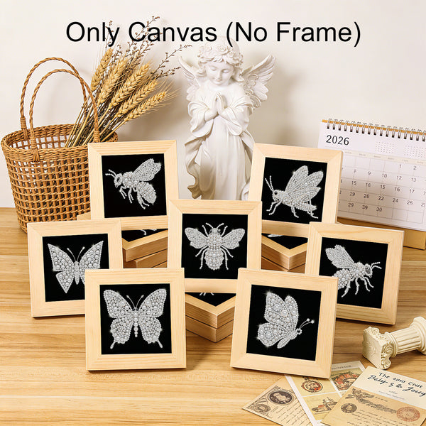Nine small canvas art prints with wooden frames are arranged on a tabletop. The prints feature silver butterfly and bee designs on a black background.