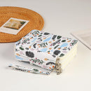 A square fabric zippered pouch with a white background and a colorful botanical print of leaves, flowers, and feathers, shown with a matching wristlet strap and metal zipper pulls on a white surface.