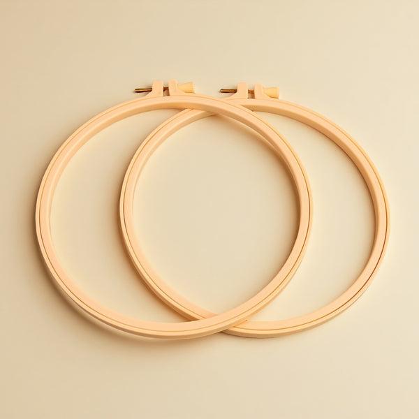 Two wooden embroidery hoops on a beige background