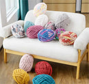 Colorful knitted yarn balls on a white sofa and floor.