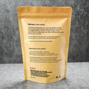 A gold resealable pouch showing the back side with printed candle preparation and usage instructions, photographed on a gray textured surface.