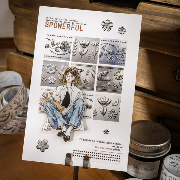 Card with illustrations and text on a stand, surrounded by stamping tools.
