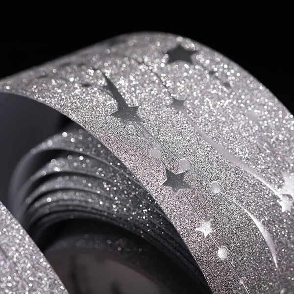 Roll of glittery black and silver decorative paper with star designs on a black background.
