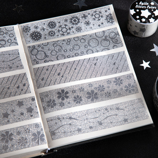Set of silver washi tape rolls with various patterns on a black surface.