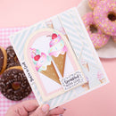 A handmade greeting card featuring two illustrated ice cream cones with cherries, held by a hand against a pink background with donuts. The card has pastel blue and white diagonal stripes, cream panels, and a small tag that reads 'Sprinkled with love'.