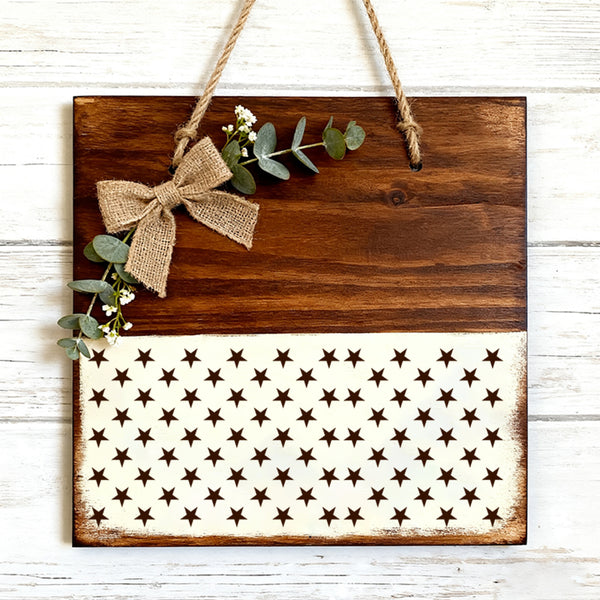 Wooden sign with American flag pattern and decorative bow on a white background