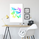 A framed wall art print featuring colorful butterfly illustrations in a bright room setting, displayed above a wooden desk with a yellow lamp and a white chair.