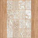 A set of 15 rectangular laser-cut stencils or templates featuring various organic, floral, and leaf patterns, arranged in a 3x5 grid on a light brown wood grain background.