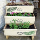 Three-tiered wooden planter with plants and decorative elements on a stone surface.