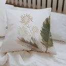 Decorative pillow with floral design and leaf on a bed