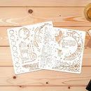 Two white laser-cut metal stencil sheets with intricate celestial and architectural designs, displayed on a light wood plank background.