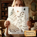 Person holding a decorative stencil with floral and butterfly design in a home setting.
