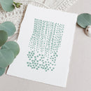 A square white art print with a mint green abstract pattern, styled flat-lay on a neutral beige surface with eucalyptus leaves and a textured white fabric background.