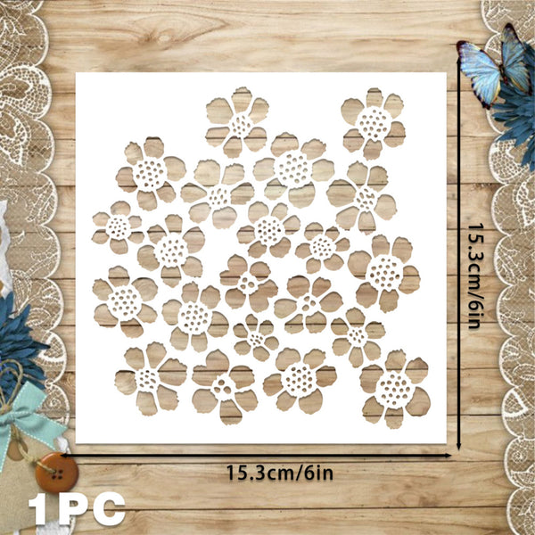 A white square stencil or template with a repeating floral cutout pattern, shown on a wood surface with dimension lines indicating 15.3 cm by 15.