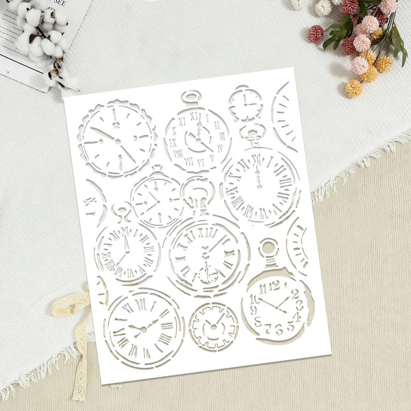 A white rectangular sheet featuring multiple cutout designs of vintage pocket watches with Roman numerals and clock faces, displayed on a light beige fabric surface with decorative flowers and cotton bolls.