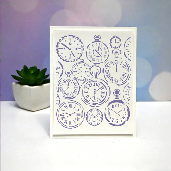 A vertical white greeting card featuring a collage of purple pocket watch illustrations, standing on a white surface with a small potted succulent and a purple bokeh background.