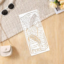 A white rectangular laser-cut paper bookmark with a leaf and script design, styled on a light wood surface with a textured cream fabric, sunglasses, a small purse, and flowers.