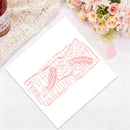 A white art print featuring a pink linocut-style illustration of a feather and text, styled on a white surface with a lace cloth, flowers, and a small bottle in the corners.