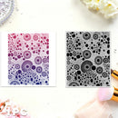 Two square art prints with circular dot patterns are displayed on a white surface. The left print features a pink-to-purple gradient, and the right print is black and white.
