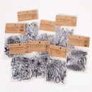 A set of multiple clear plastic craft sticker sheets featuring black and white botanical illustrations, each with its own kraft paper label card. The designs include flowers, leaves, ferns, and roses.