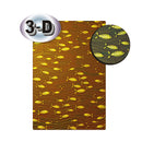 A rectangular decorative panel or wallpaper sample with a 3-D effect, featuring a pattern of yellow fish swimming over wavy brown and gold lines. An oval badge with the text '3-D' is in the top-left corner, and a circular inset on the right shows a close-up of the fish pattern.