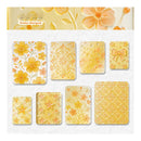 A sheet of decorative stickers or stamp designs in a warm golden marigold color, featuring floral, ornamental, raindrop, bow, star, and patterned motifs on a white textured background.