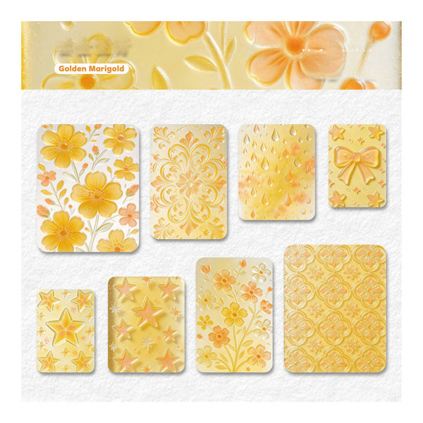 A sheet of decorative stickers or stamp designs in a warm golden marigold color, featuring floral, ornamental, raindrop, bow, star, and patterned motifs on a white textured background.