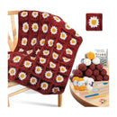 Crocheted daisy-pattern blanket draped over a wooden chair, shown with a small inset of a finished square patch and a round table holding yarn balls, knitting needles, and a booklet.