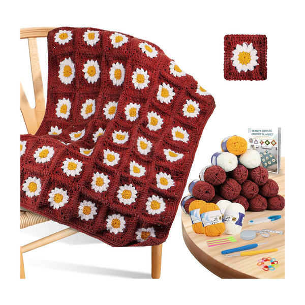Crocheted daisy-pattern blanket draped over a wooden chair, shown with a small inset of a finished square patch and a round table holding yarn balls, knitting needles, and a booklet.