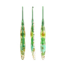 Three green-handled glass crochet hooks with dried flower and leaf inclusions, displayed vertically on a plain white background.