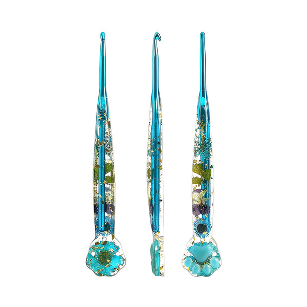 Three glass crochet hooks with blue handles and embedded dried flowers, shown from front, side, and back views on a white background.