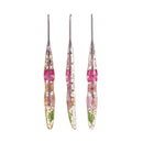 Three elongated clear resin tools with metal tips, each containing pressed pink flowers, pale petals, and small green botanical elements, arranged vertically on a white background.