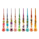 Nine colorful glass nail art tools arranged in a row on a white background, each filled with pressed flowers and greenery in different hues including pink, blue, purple, green, and orange.