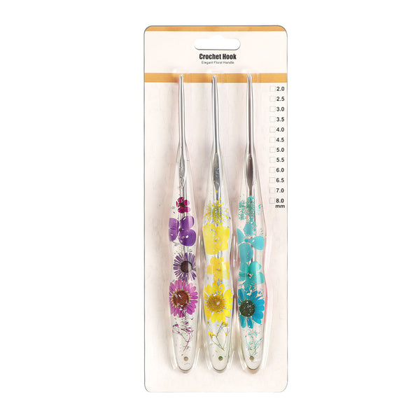 Four crochet hooks in a clear plastic case with floral handles, attached to a white cardboard hanger labeled 'Crochet Hook' with size markings, on a white background.