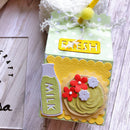 Decorative milk carton with 'Fresh Milk' label and floral design on a wooden surface.