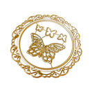 A circular gold metal die-cut embellishment featuring a central butterfly motif, three smaller butterflies above it, and an ornate filigree border around the edge, shown on a plain white background.