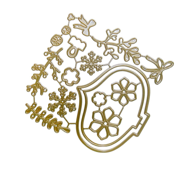 A gold metal die-cut craft sheet featuring winter-themed designs including snowflakes, pinecones, leaves, and a shield with floral motifs, isolated on a white background.