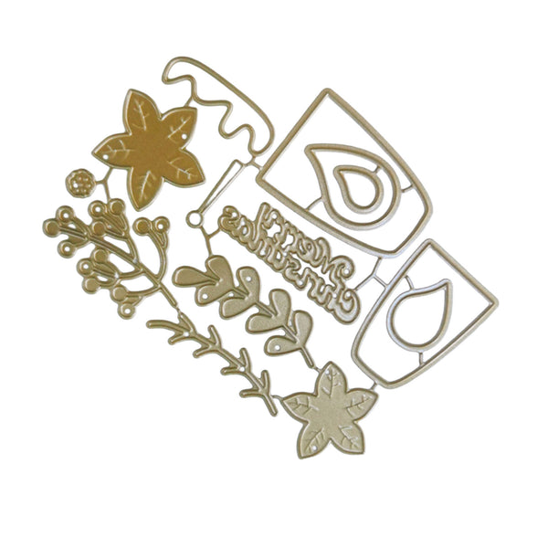 A gold metal die-cut craft embellishment featuring floral motifs, berries, and a script word reading 'Grimgrimm' on a plain white background.
