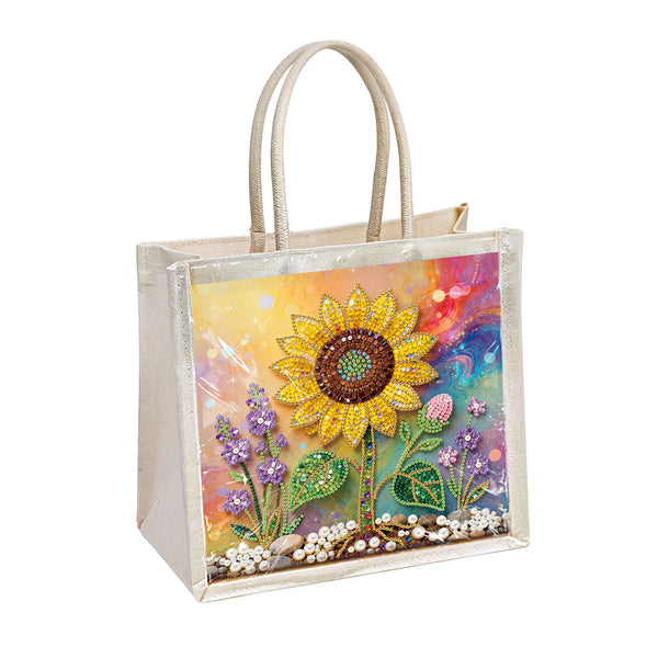 A clear plastic tote bag with beige handles, decorated on the front with a colorful diamond painting or bead design featuring a large yellow sunflower and purple flowers against a rainbow background.