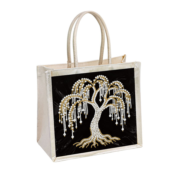 A structured tote bag with a black front panel featuring a large jeweled tree design in gold and white, and a metallic champagne-gold frame with matching handles.