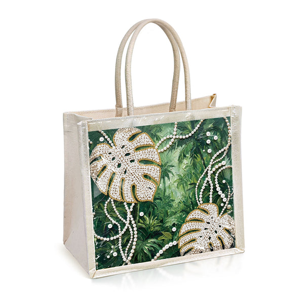 A clear plastic tote bag with a beige handle and trim, featuring a printed tropical design on the front. The print shows green palm leaves and monstera leaves embellished with white rhinestones, accented by white faux pearl strands, all set against a plain white background.