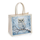 A square canvas tote bag with a winter owl design on the front panel. The bag has a light beige canvas body, beige shoulder straps, and a printed design of a detailed white owl with gold eyes perched on a snowy branch against a blue winter sky background.